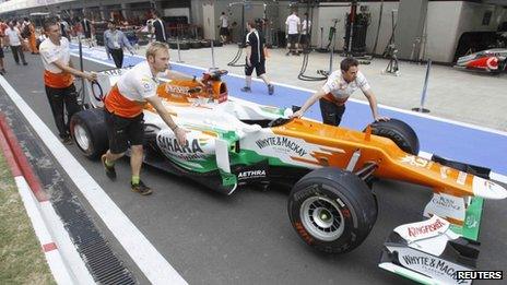 Pit crew push the car of Force India Formula 1 driver Paul di Resta of Britain in the pit lane at the Buddh International Circuit