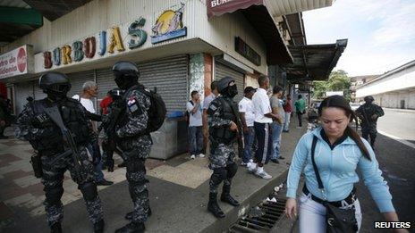 Policemen stand guard after stores were looted during protests against the law on 26 October.