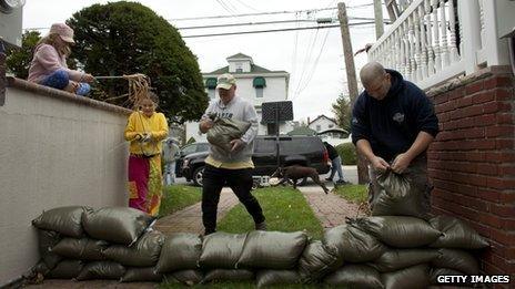 Families install a wall of sandbags to protect their basement in Queens, New York, October 28