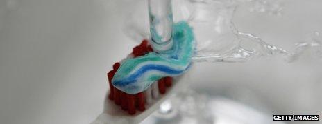 Water splashing onto a toothbrush with toothpaste on it