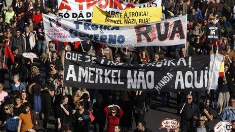 Demonstrators hold banners protesting the visit to Portugal of German Chancellor Angela Merkel, Lisbon, 12 Nov