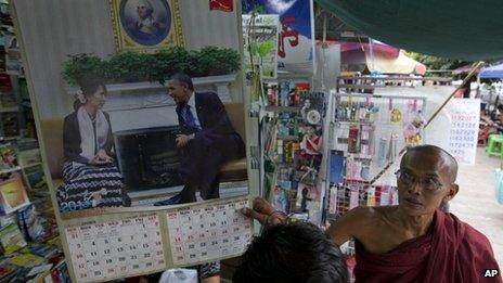 A Buddhist monk looks at a calendar with photographs of American President Barack Obama and Myanmar's opposition leader Aung San Suu Kyi