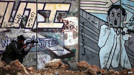 Israeli soldier in front of graffiti