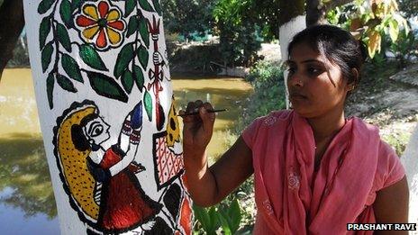 A Madhubani artist painting the traditional art form on a tree trunk