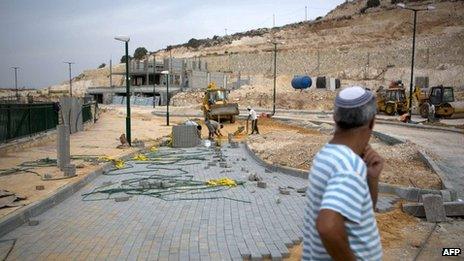 An Israeli settler observes Palestinian labourers working on the expansion of the Jewish settlement of Tzufim near the West Bank town of Qalqilya