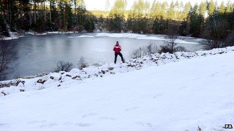 A person looks at ice while surrounded by snow at Kielder Water, Northumberland