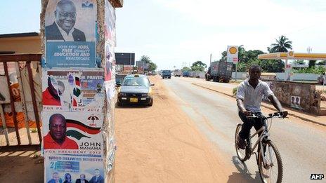 Man in Ghana cycles past presidential election posters featuring President John Dramani Mahama and his main challenger, Nana Addo Dankwa Akufo-Addo, on 23 October 2012