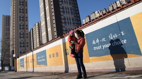 A mother plays with her child on the street that leads to the Jingyuan Road public housing project, the largest one in Beijing