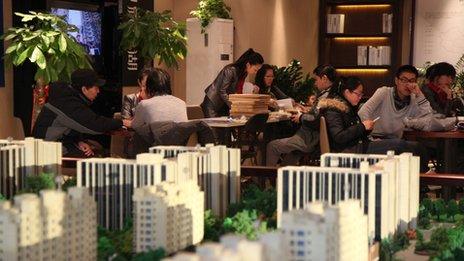 Sales representatives talk to customers behind the East Asia Impression Lake real estate building models