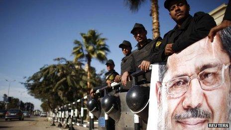 Police stand guard near a banner outside the constitutional court put up by supporters of President Mohamed Morsi, 23 Dec