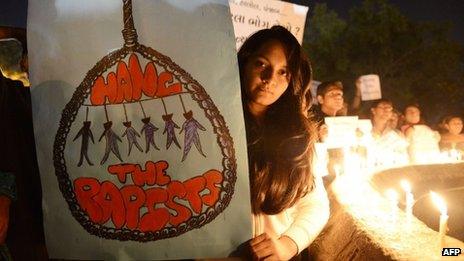 Протестующие держат свечи и плакаты во время митинга в Ахмадабаде 30 декабря 2012 г.