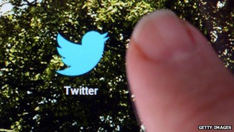 Finger hovering over Twitter icon on touchscreen phone