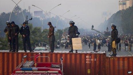 Pakistani police officers stand guard atop shipping containers while supporters of Pakistan Sunni Muslim cleric Tahir-ul-Qadri stage an anti government rally in Islamabad, Pakistan on Tuesday, Jan. 15, 2013.