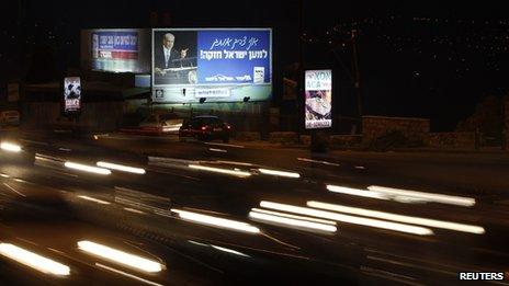 Cars drive past election posters in Jerusalem