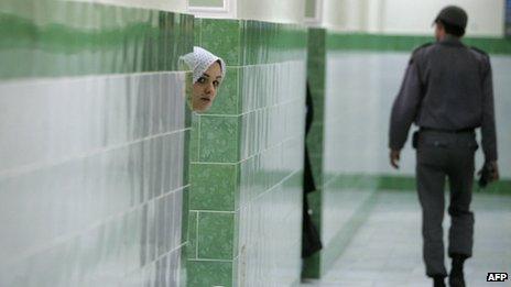 Фотография из файла: женщина-заключенная выглядывает из-за стены, когда мимо проходит охранник в женском отделении тюрьмы Эвин (июнь 2006 г.)