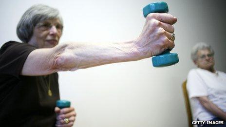 An elderly lady takes part in a fitness class