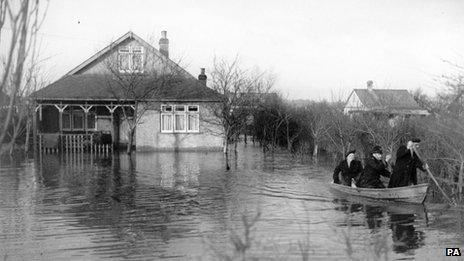 A policeman and rescue worker rowing a flood victim from her home at Canvey Island, Essex