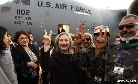 Hillary Clinton flashes the V for victory sign with Libyan fighters loyal to the National Transitional Council, 2011