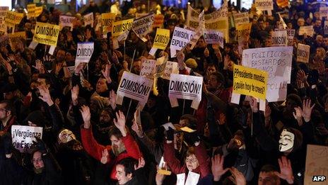 Protesters in Madrid holding banners reading 'Resign' (2 February 2013)