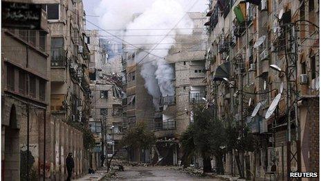 Smoke rises from a deserted street in Zamalka, Damascus
