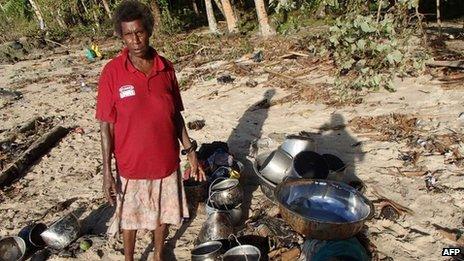 A resident with salvaged possessions from her destroyed home in the village of Venga, Solomon Islands, on 7 February 2013