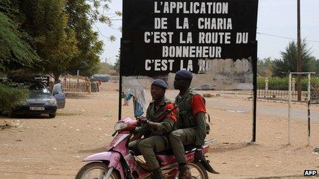 Malian soldiers on a motorcycle by a Sharia sign - 12 February 2013