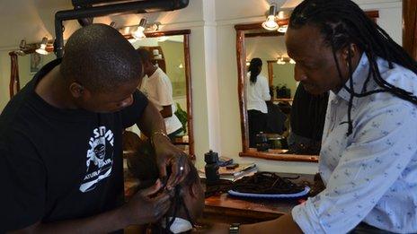 Hair stylist and business man Jabu Stone coaches a stylist on how to insert dreadlock extensions at his salon in Rivonia, Johannesburg