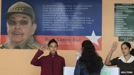 Schoolgirls salute as a woman casts her ballot to elect a Communist Party-selected slate of 612 deputies to the National Assembly (3 February 2013)