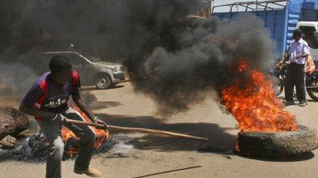 A protester prods a burning tyre roadblock as he and others take to the streets to protest the results of the Orange Democratic Movement (ODM) primary elections in Kisumu in January 2013