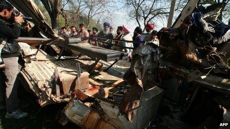 Indian villagers look at the damaged school bus in which at least eleven school children died when the school bus collided with a truck in Jaheer village, in Jalandhar district on March 4, 2013.