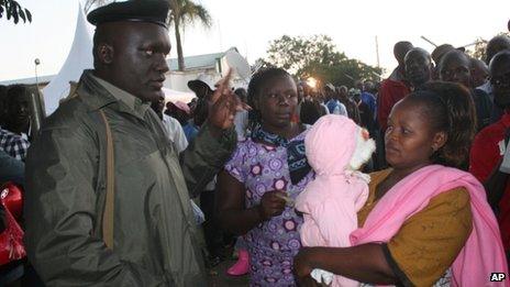A woman holding her child is assisted by a police officer in Kisumu, Kenya -Monday 4 March 2013