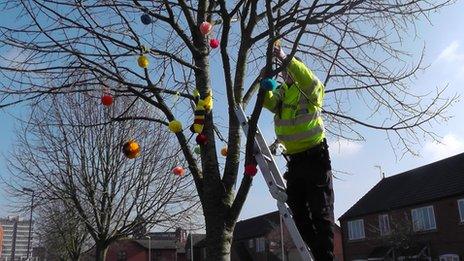 Police officer attaching pom-poms to a tree