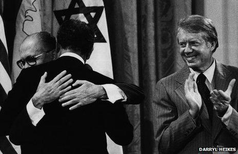 President Jimmy Carter claps as Israeli Prime Minister Menachem Begin and Egyptian President Anwar Sadat embrace after signing the historic Camp David Accords (Darryl Heikes Photographs Dolph Briscoe Center for American History The University of Texas at Austin)