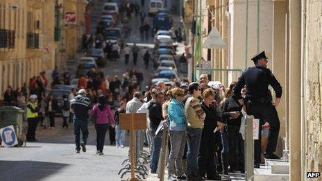 People queue outside a polling station during the National elections of Malta on March 9