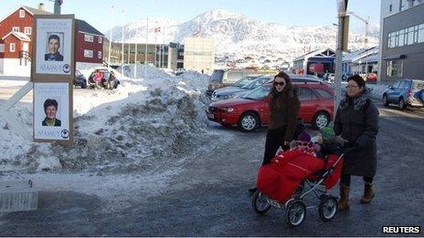 Locals walk past campaign posters in the centre of Nuuk on Monday