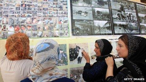 Women weep as they look at photos of the dead in Halabja