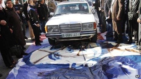 A man drives a taxi over a painting of Barack Obama in Ramallah (18 March 2013)