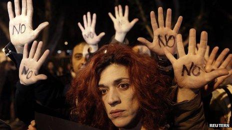 Anti-bailout protesters raise their open palms showing the word "No" after Cyprus"s parliament rejected a proposed levy on bank deposits