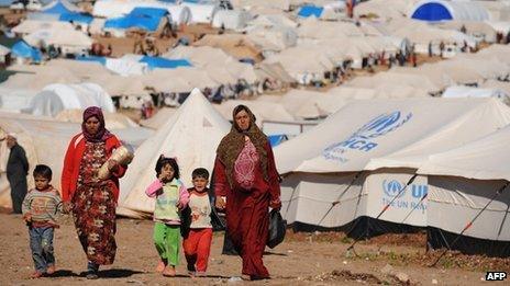 Syrian internally displaced people walk in the Atme camp, along the Turkish border