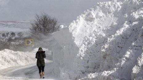 A woman walks past a snow drift