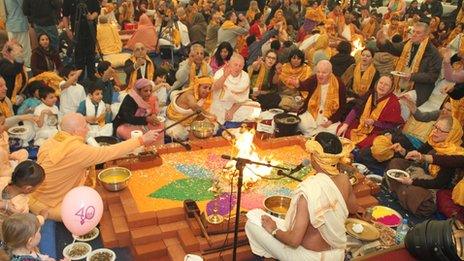 Hare Krishna congregation chant prayers around a sacred fire