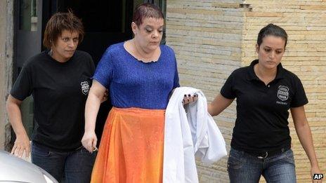 Dr Virginia Helena Soares de Souza, centre, who is charged with killing seven patients, is escorted by police officers to a temporary prison in Curitiba, Parana state, Brazil on 19 February 2013