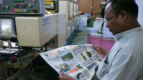 Printer and publisher U Win Htay looks at the front page of his new daily, Standard Time, one of the first four private daily newspapers to be produced in Burma for half a century