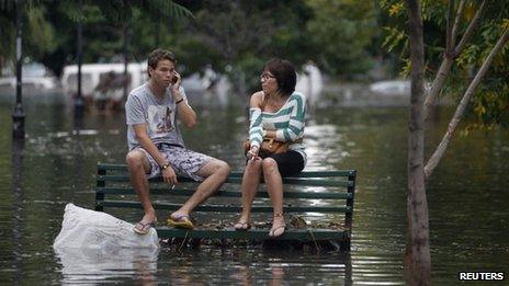 Residents sit on a bench in a flooded Buenos Aires street