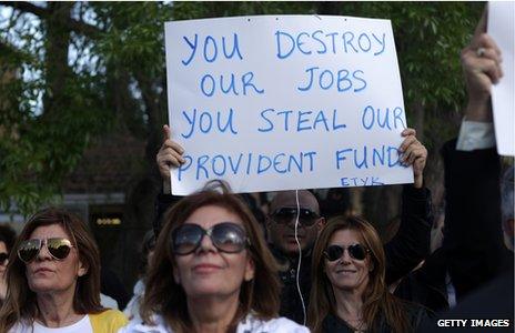 A protestor holding a sign saying "You destroy our jobs, you steal our provident funds"