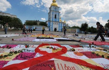 People walk past quilts laying on Mikhaylovskaya Square in Kiev made by HIV positive people to commemorate AIDS victims in Ukraine