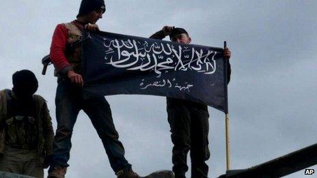 Rebels from the al-Nusra Front waving their brigade flag on the top of a Syrian air force helicopter