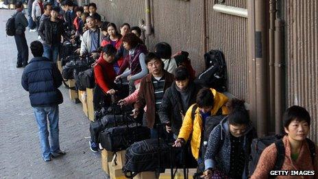 Visitors from mainland China wait in a queue with their goods outside the Sheung Shui train station in Hong Kong