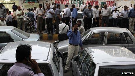 Office workers stand outside their buildings following an earthquake tremor in Karachi on 16 April 2013