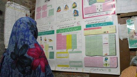 Mumtaz Begum looks at a health department poster in her bedroom
